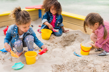 Three children playing in sandbox.